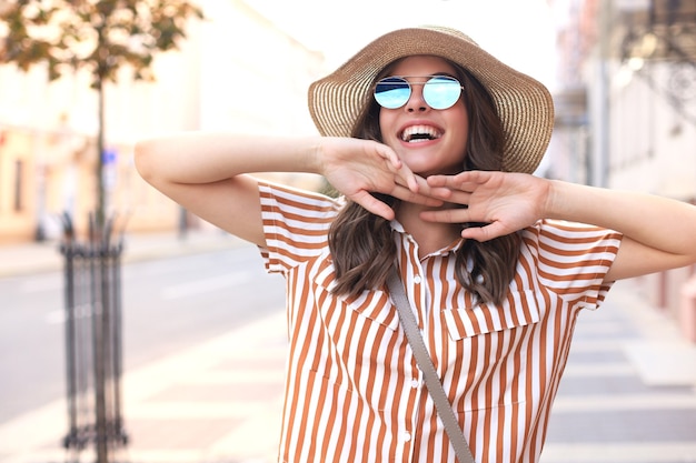 Portrait fashion woman is posing in the city, summer street fashion. Laughing and smiling portrait.