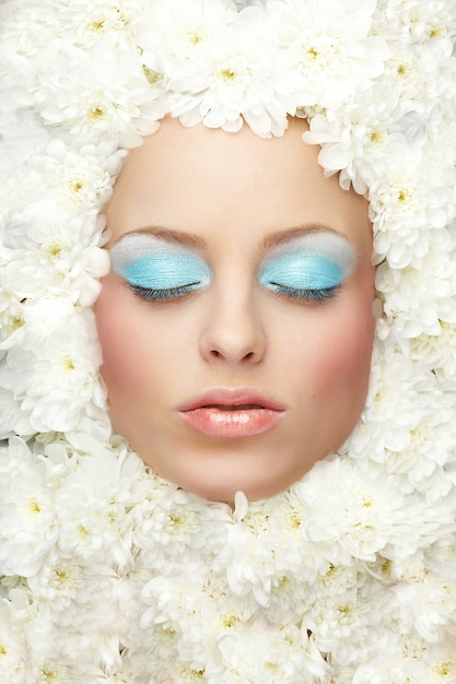 Portrait of fashion woman model with bright makeup lies in flowers