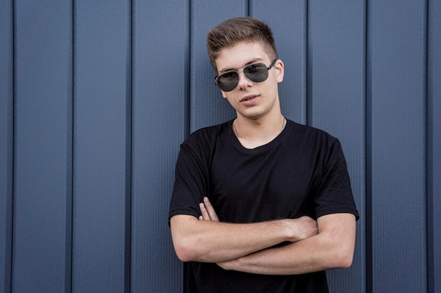 Portrait of a fashion young man leaning against a blue wall