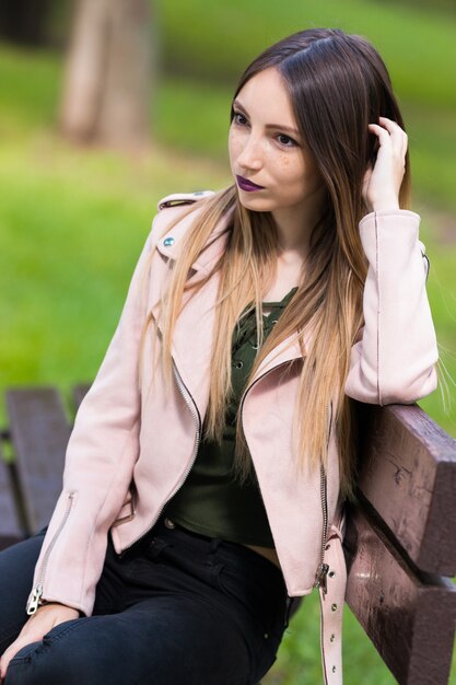Портрет модной девушки на скамейке в парке