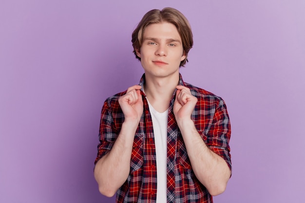 Portrait of fashionable stylish cool guy adjust shirt collar look camera on purple background