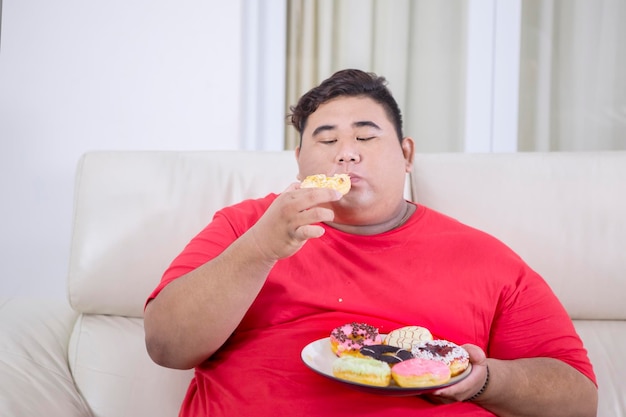 Portrait of fat Asian man biting a doughnut