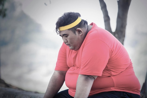 Портрет толстого азиатского мужчины, отдыхающего после бега