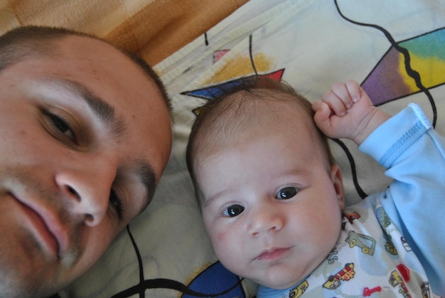 Photo portrait of father and cute baby on bed