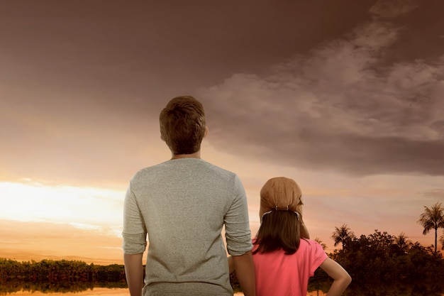 Portrait of father and daughter enjoying sunset view 