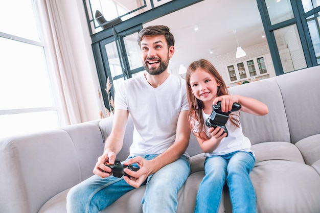 Portrait of father and daughter playing computer game in living room