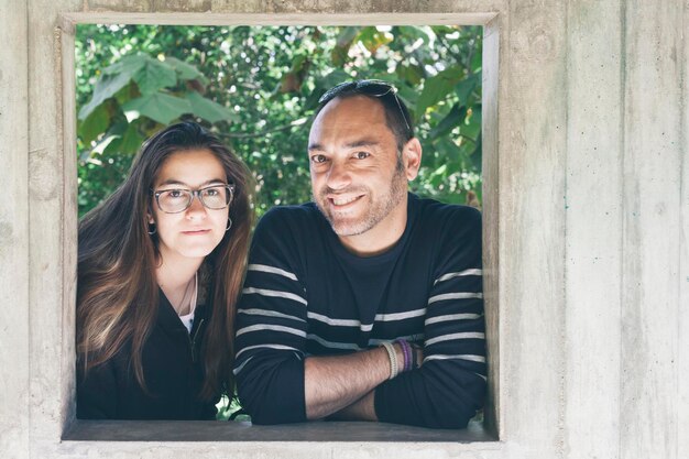 Photo portrait of father and daughter standing behind square shape window frame