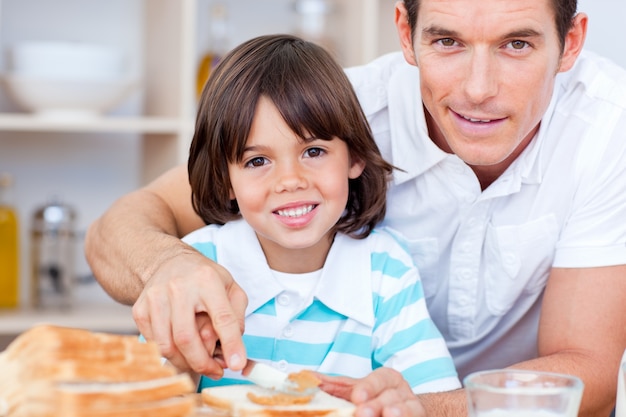 Portrait of a father and his son spreading jam on bread