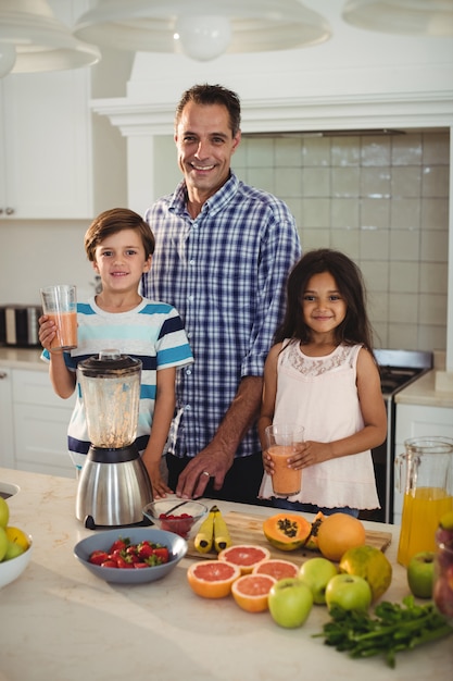 Portrait of father and kids holding glass of smoothie