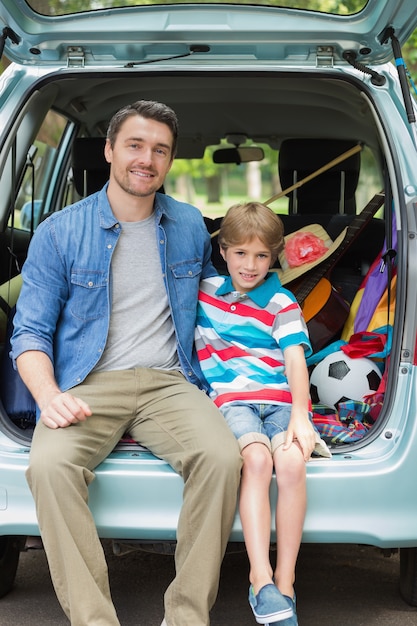 Photo portrait of father and son sitting in car trunk