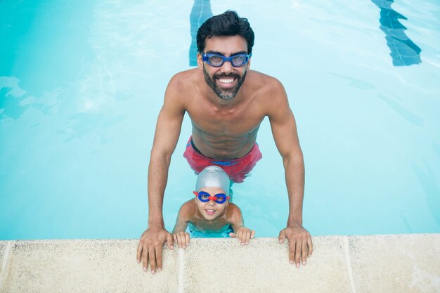 Ritratto di padre e figlio che indossano occhiali da nuoto in piscina