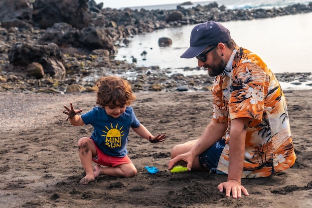 Ritratto di padre con suo figlio che gioca sulla spiaggia di sabbia nera di valle gran rey a la gomera isole canarie