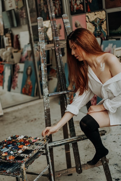 Portrait of female artist with brush in art workshop