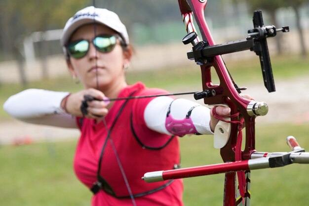 Portrait of female athlete practicing archery in stadium.