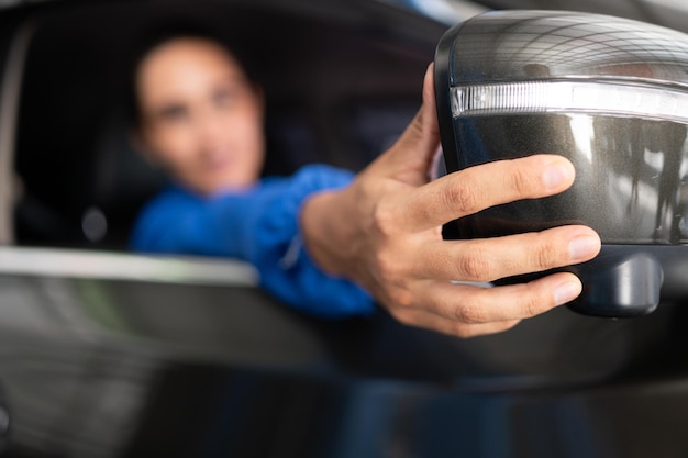 Portrait of female auto mechanic sitting behind steering wheel in a car