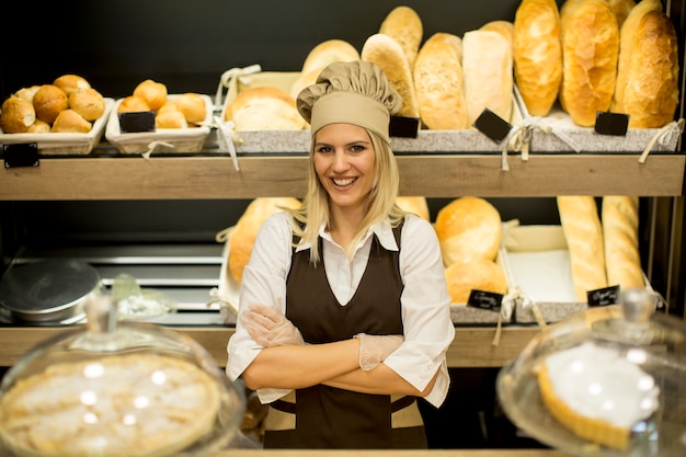 Portrait of female baker with fresh bread smiling in bakery