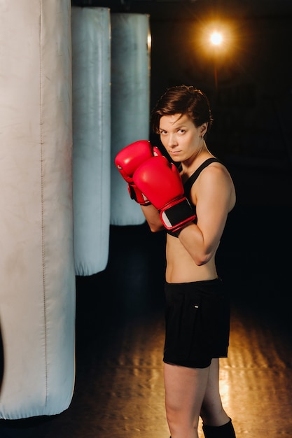 Portrait of a female boxer in red gloves in the gym during training