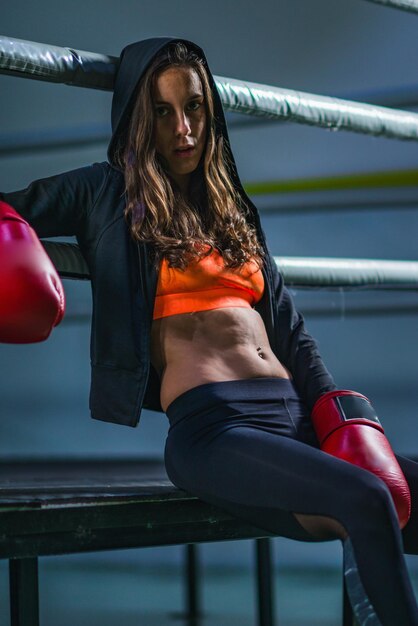 Photo portrait of female boxer sitting on boxing ring