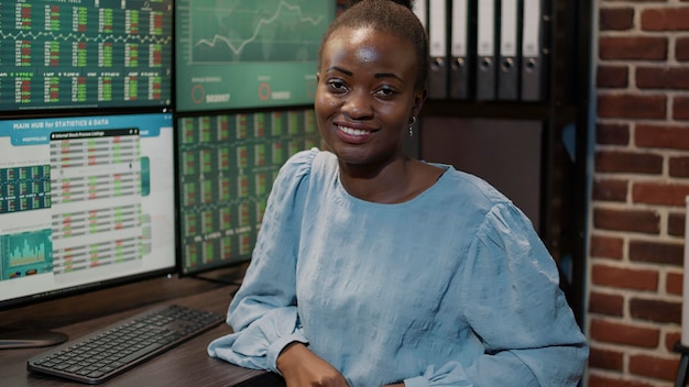 Portrait of female broker using multi monitors to watch trade market numbers, global money exchange. Financial trading with profit share and hedge fund index, monitoring statistics.