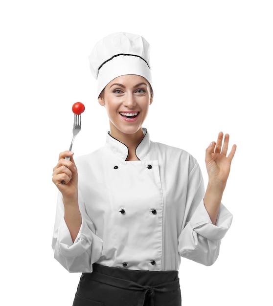 Portrait of female chef holding fork with cherry tomato on white