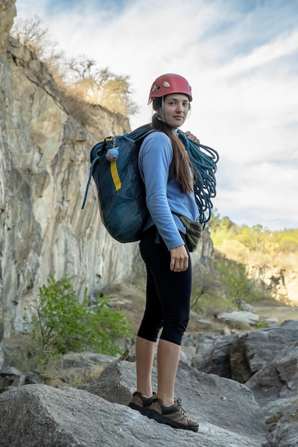 岩の山の足元でカメラを見ている女性登山者の肖像画 エクストリームアウトドアスポーツ