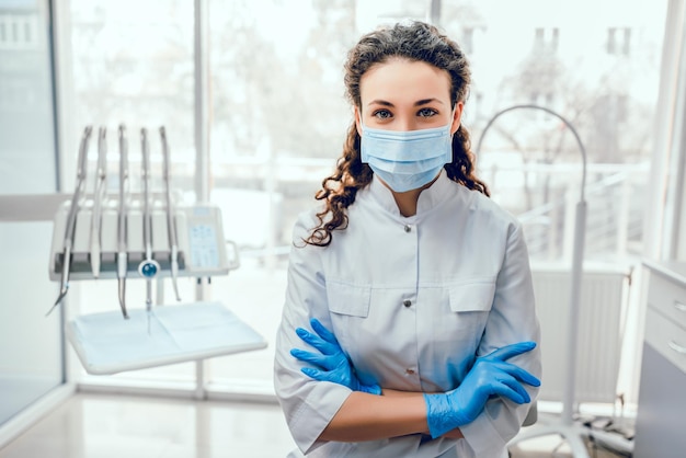 Foto ritratto di dentista femminile lei in piedi nel suo ufficio in maschera