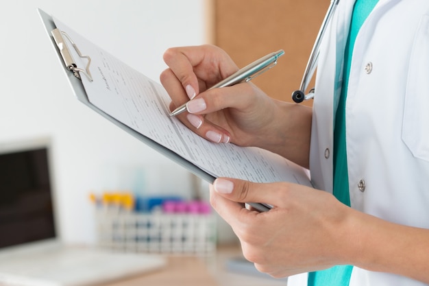 Portrait female doctor at hospital writing prescription