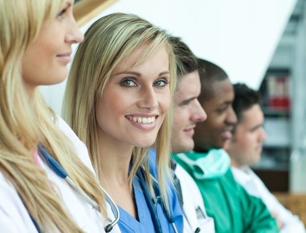 Photo portrait of female doctor smiling at the camera with her team in a line on stairs