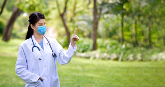 Photo portrait of a female doctor standing in the park and pointing