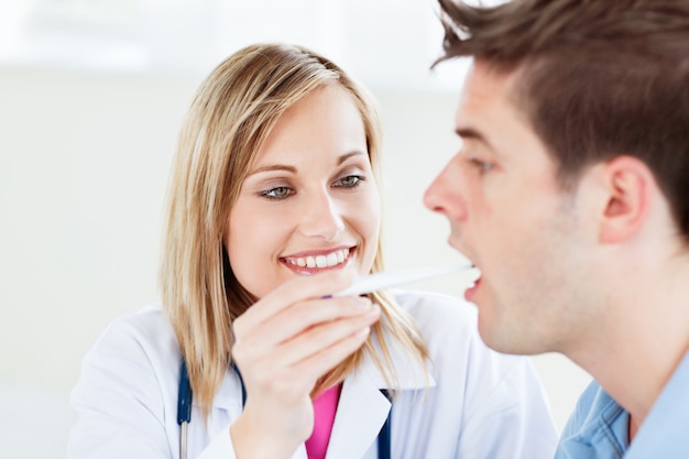 Portrait of a female doctor taking a saliva sample of a male patient with cottonbud