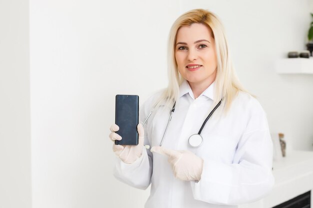 Photo portrait of female doctor using her mobile phone in the consultation.