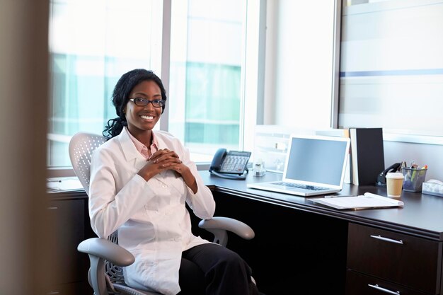 Portrait Of Female Doctor Wearing White Coat In Office