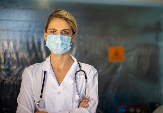 Portrait of female doctor with protective mask. Hospital background.
