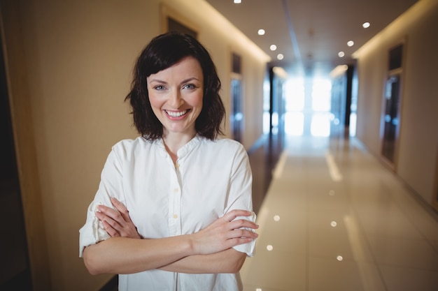 Portrait of female executive standing with arms crossed in corridor