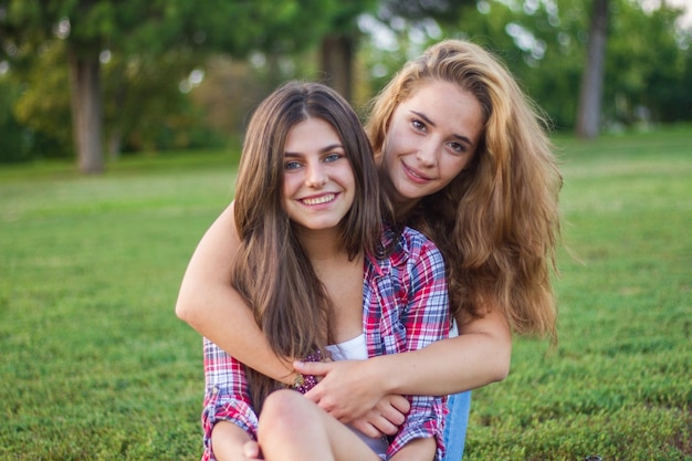 Photo portrait of female friends embracing on field at park