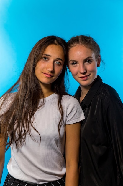 Photo portrait of female friends smiling while standing against blue background