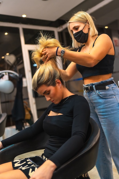 Portrait of a female hairdresser in a medical mask doing her job new normal