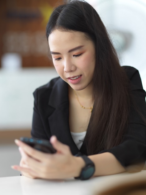 Portrait of female hands using smartphone on table in office room