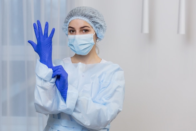 Portrait of a female medic, in a protective blue suit, and a medical mask on her face