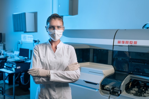 Portrait of a female in  medical coat and  safety glasses researcher carrying out research in a chemistry lab posing on Laboratory
