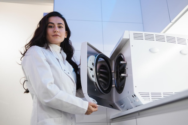 Portrait of female medical worker with autoclave to sterilize the instrument