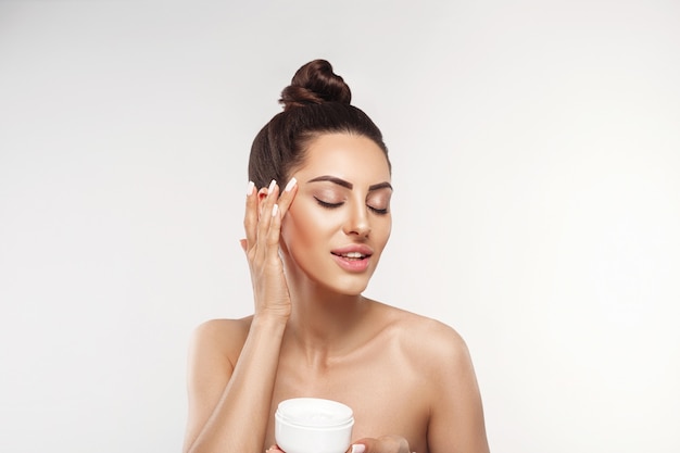 portrait of female model holding and applying cosmetic moisturizing cream