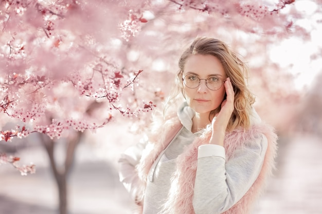 Portrait of female model near pink peach blossom tree