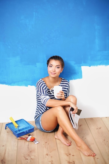 Portrait of female painter sitting on floor near wall after painting