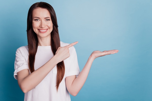 Portrait of female person hold hand point empty space option isolated of blue background