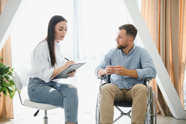 Portrait of female psychiatrist interviewing handicapped man during therapy session copy space