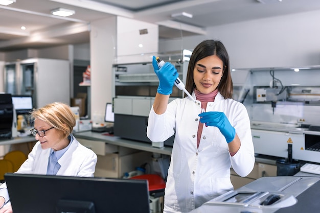 Foto il ritratto della scienziata con una pipetta analizza un liquido per estrarre il dna e le molecole nelle provette in laboratorio concetto di ricercabiochimica medicina farmaceutica