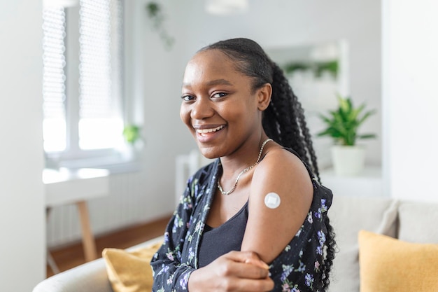 Photo portrait of a female smiling after getting a vaccine woman holding down her shirt sleeve and showing her arm with bandage after receiving vaccination