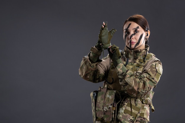 Portrait of female soldier in camouflage on dark wall