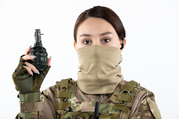 Portrait of female soldier with grenade in camouflage white wall